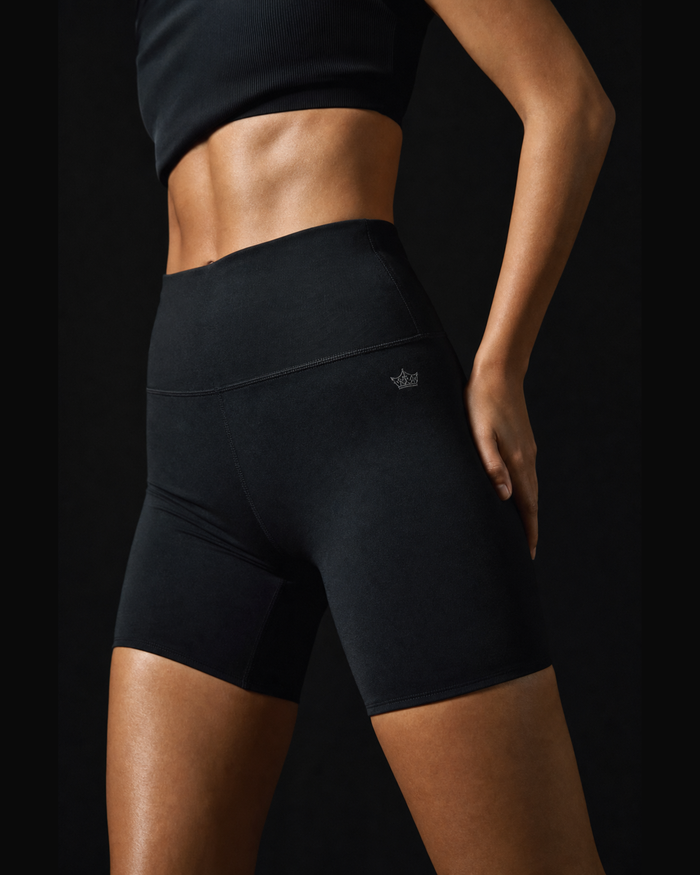 Model wearing Originals CA black high-waisted biker shorts with crown, studio portrait
