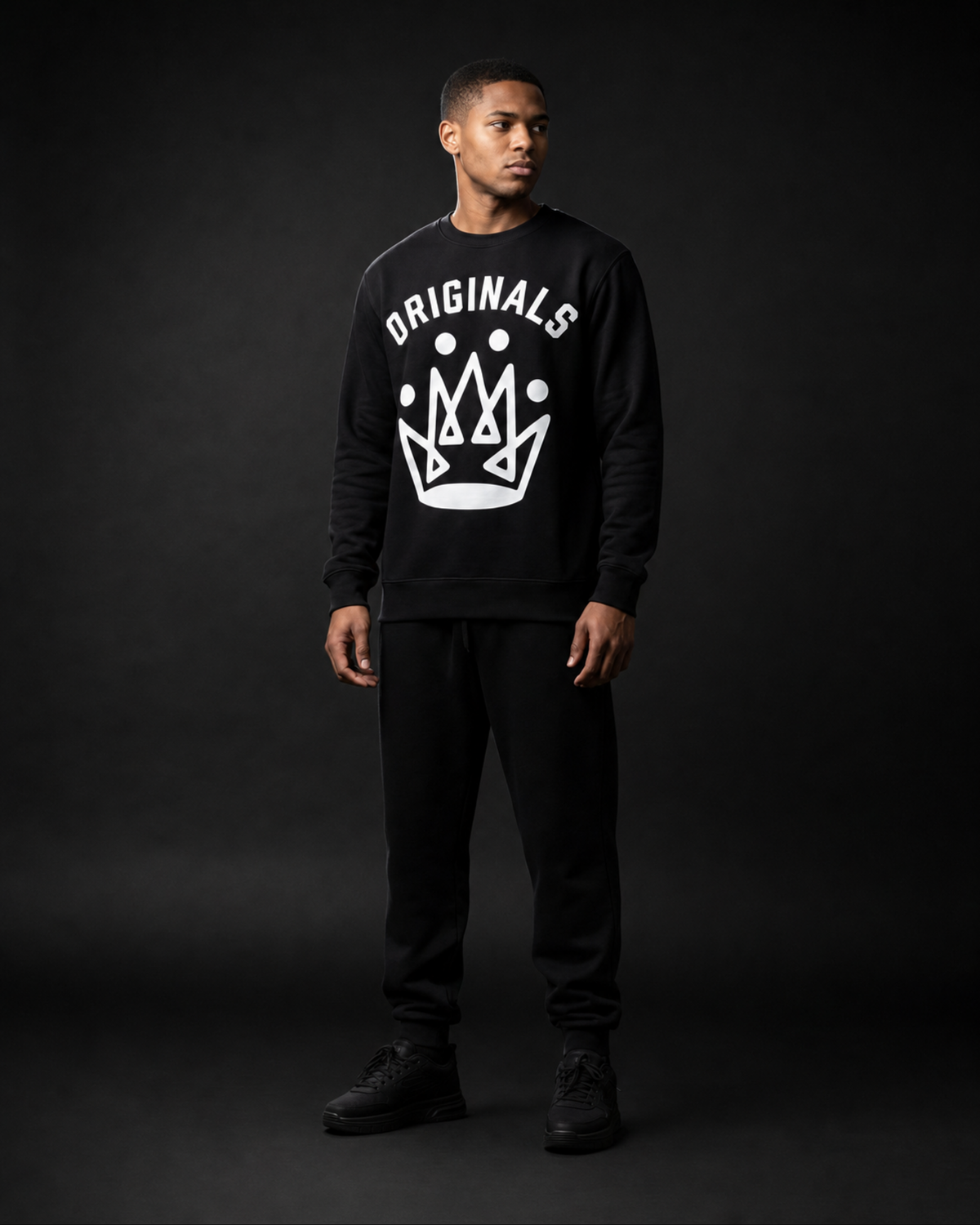 Model wearing Originals CA matte black crewneck sweatshirt with crown emblem, studio portrait