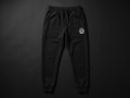 Model wearing Originals matte-black sweatpants with small white crown at hip