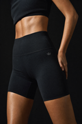 Model wearing Originals black high-waisted bike shorts with crown embroidery